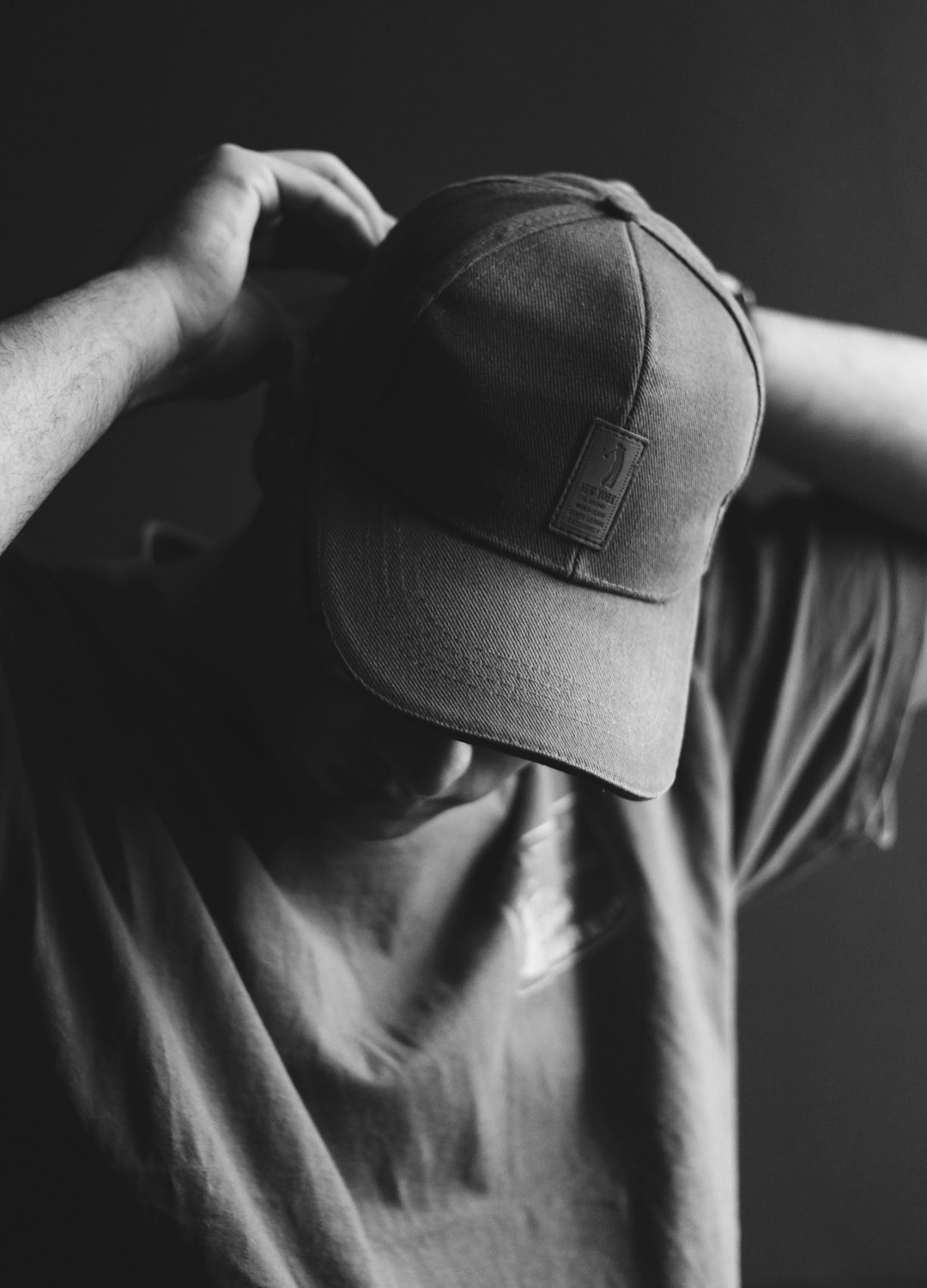 Person adjusting a baseball cap with text visible.